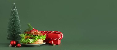 Noel dekorlu lezzetli hamburger ve yeşil arka planda mesaj için yeri olan hediye.