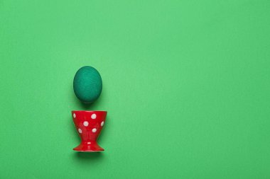 Yeşil arka planda boyanmış Paskalya yumurtası ve tutacağı.