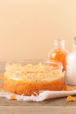 Vücut fırçası kavanozu ve deniz tuzu şişeleri ahşap masada, duvarın yanında, yakın plan.