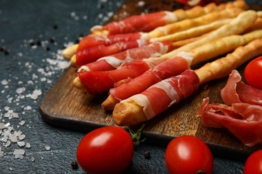 Lezzetli İtalyan Grissini ahşap tahtası. Arka planda pastırma, yakın plan.