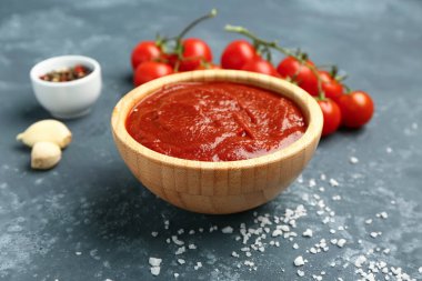 Gri grunge arka planda lezzetli domates ezmesi, sarımsak ve baharatlı kase.