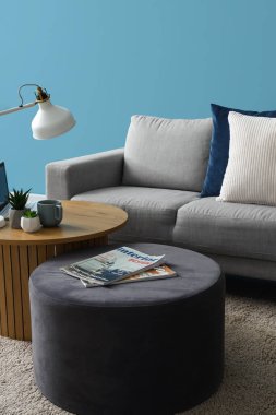 İçinde dergiler, modern dizüstü bilgisayarlar ve oturma odasının iç kısımlarında ev bitkileri olan puf ve kahve masası.