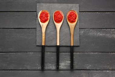 Koyu ahşap arka planda lezzetli domates soslu kaşıklar.