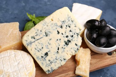 Ahşap tahta, mavi arka planda farklı çeşitte lezzetli peynir var.