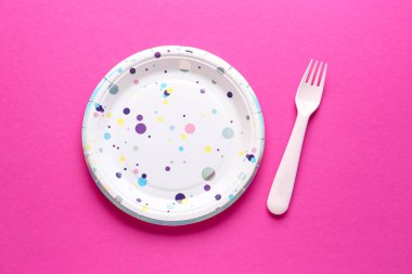 Pembe arka planda tek kullanımlık kağıt ve çatal.