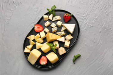 Gri arkaplanda lezzetli peynir parçaları olan tepsi