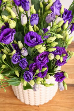 Ahşap masa arkasında Eustoma çiçekleri olan vazo