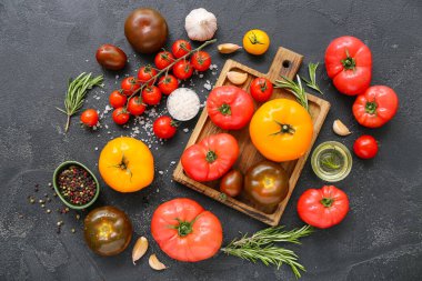 Siyah zemin üzerinde farklı taze domatesler olan tahta.