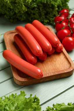 Lezzetli ince sosisler ve yeşil ahşap arka planda marul.