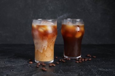 Siyah arka planda sütlü bir bardak lezzetli buzlu kahve.