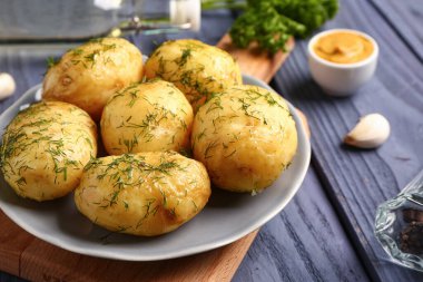 Mavi ahşap arka planda dereotlu haşlanmış bebek patatesler.