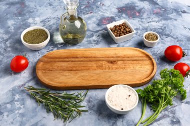 Ahşap mutfak tahtası, taze baharatlar, otlar ve domateslerle renklendirilmiş.