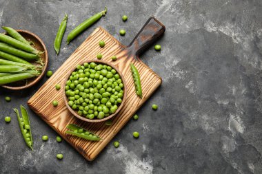 Siyah arka planda taze bezelyeler ve ahşap tabaklar.