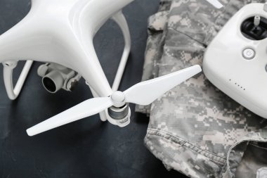 Modern kuadkopter, askeri üniforma ve siyah arka planda uzaktan kumanda.