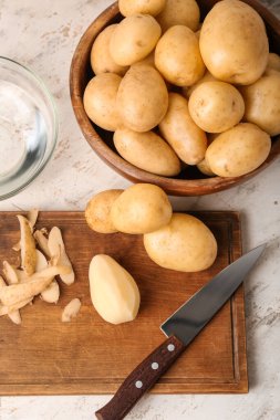 Tahta tahta ve kase ve beyaz arka planda çiğ patates.