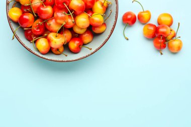 Mavi arka planda sarı kirazlı bir kase.