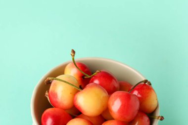 Turkuaz arka planda sarı kirazlı bir kase.