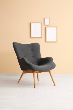 Şık siyah koltuk ve bej duvarın yanındaki çerçeveler.