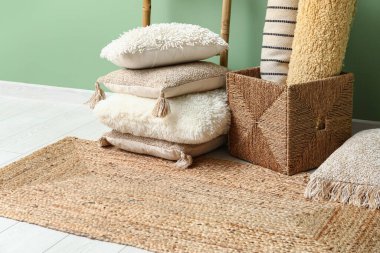 Carpets, cushions and wicker rug near green wall