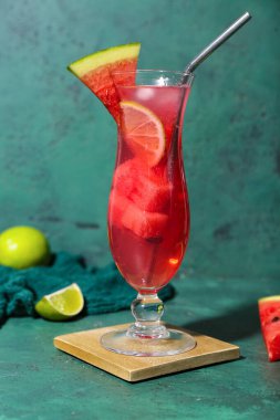Bir bardak lezzetli karpuz kokteyli ve yeşil arkaplanda limon.