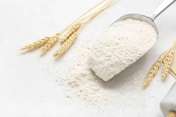 Beyaz arka planda buğday unu ve dikenli dikenli kepçeyle