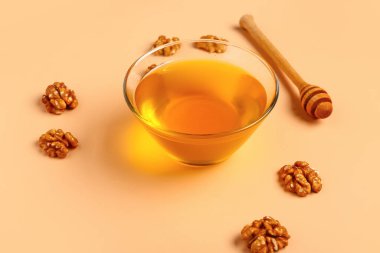 Bej arka planda ceviz ve dipli bir kase tatlı bal.