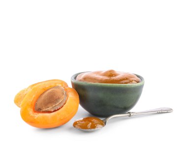 Beyaz arka planda tatlı kayısı reçeli kâse ve kaşık