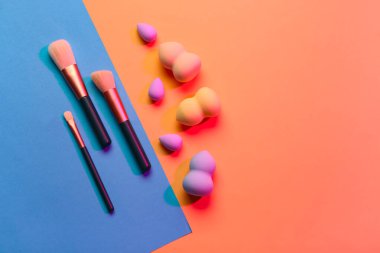 Renkli arkaplanda makyaj süngerleri ve fırçalar