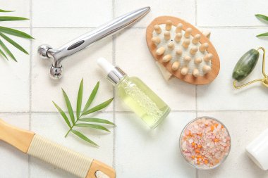 Yüz masajı silindirleri, kozmetik ürünler ve arka planda hafif fayans fırçaları