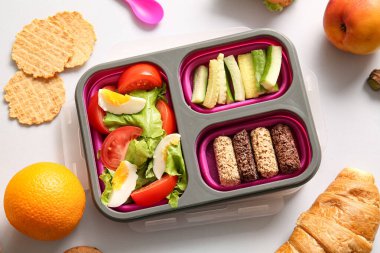 Beslenme çantasında beyaz arka planda farklı lezzetli yiyecekler var.