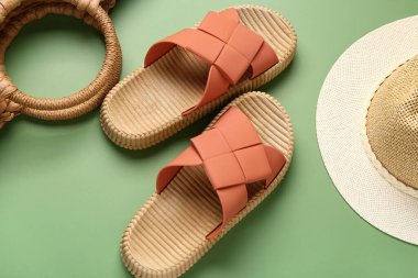 Yeşil arka planda plaj aksesuarları olan şık bayan terlikleri.