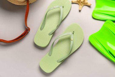 Gri arka planda plaj aksesuarları olan şık bayan terlikleri.