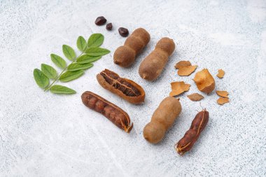 Beyaz arka planda lezzetli tamarindler, kabuk, tohumlar ve yapraklar