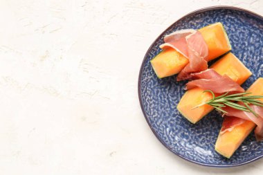 Lezzetli kavunlu tabak ve arka planda jambon.