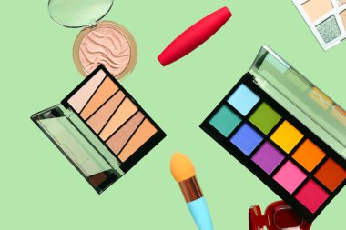 Yeşil arka planda uçan dekoratif kozmetik ürünleri