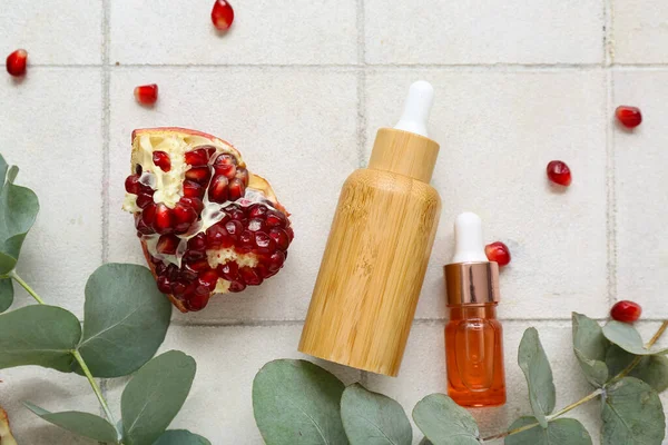 Temel yağ şişeleri, nar ve okaliptüs dalları hafif fayans zemin üzerinde, yakın çekim bileşimi