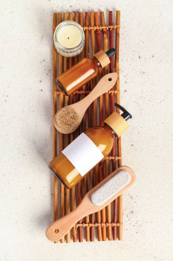 Kozmetik ürünleri şişeleri, masaj fırçaları ve yanan mum içeren kompozisyon