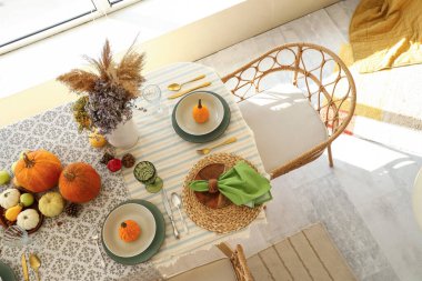 Yemek masasında balkabağı ve çiçeklerle sonbahar ayarı.