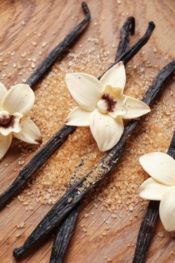 Aromatik vanilya şekeri, çiçekler ve tahta arka planda çubuklar