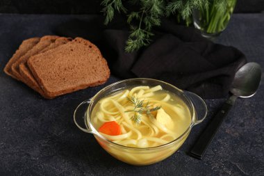 Siyah arka planda lezzetli tavuk çorbası ve ekmek.