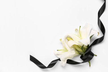 Beyaz arka planda siyah cenaze kurdelesi olan güzel zambak çiçeklerinden yapılmış çerçeve.