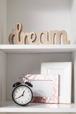 Alarm saati, fotoğraf çerçevesi ve dekorlu raf ünitesi