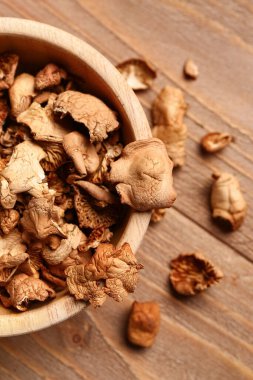 Ahşap arka planda lezzetli kurutulmuş mantarlı kase, yakın plan.