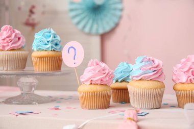 Masada pembe arka planda soru işareti ve süslemeleri olan enfes kekler. Cinsiyet ortaya çıkan parti kavramı