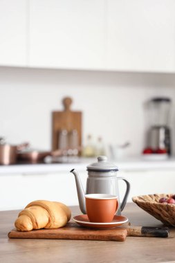 Mutfak masasında çaydanlık, çay ve kruvasan modern mutfakta.