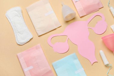 Kağıt rahim ve farklı kadın hijyen ürünleri içeren kompozisyon renk arkaplanı