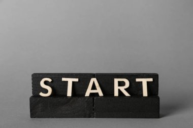 Gri arkaplanda Başlat sözcüğüyle siyah bloklar