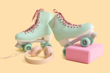 Sarı arka planda patenler ve kulaklıklar.