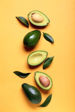 Taze olgun avokadolar ve turuncu arka planda yapraklar.
