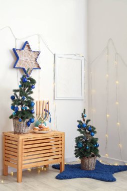 Parlayan ışıkları, köknar ağaçları ve geleneksel Hanuka süslemeleri olan festival salonu.